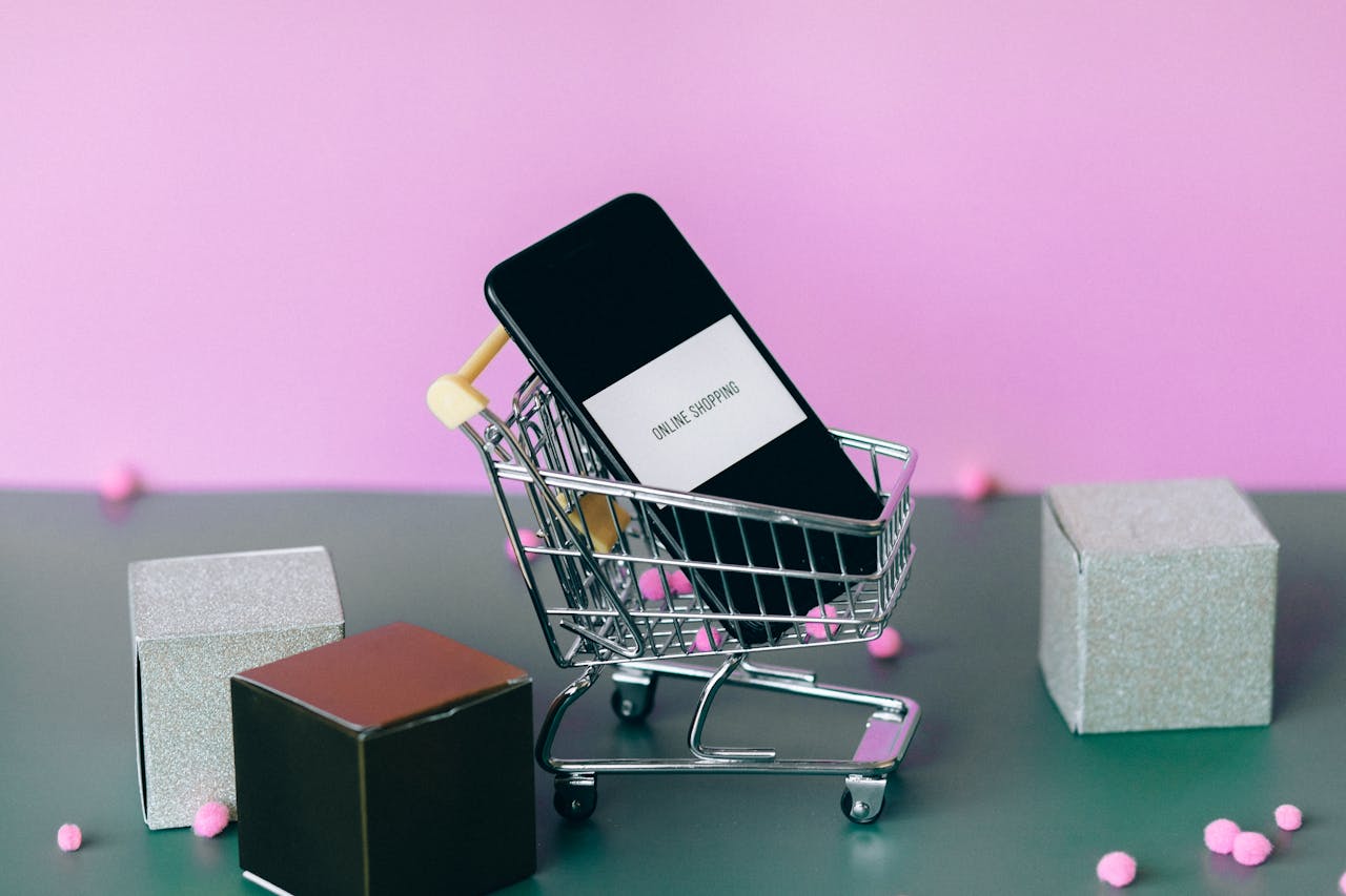 home-img A smartphone with a shopping cart depicting the concept of online shopping in a colorful studio setup.